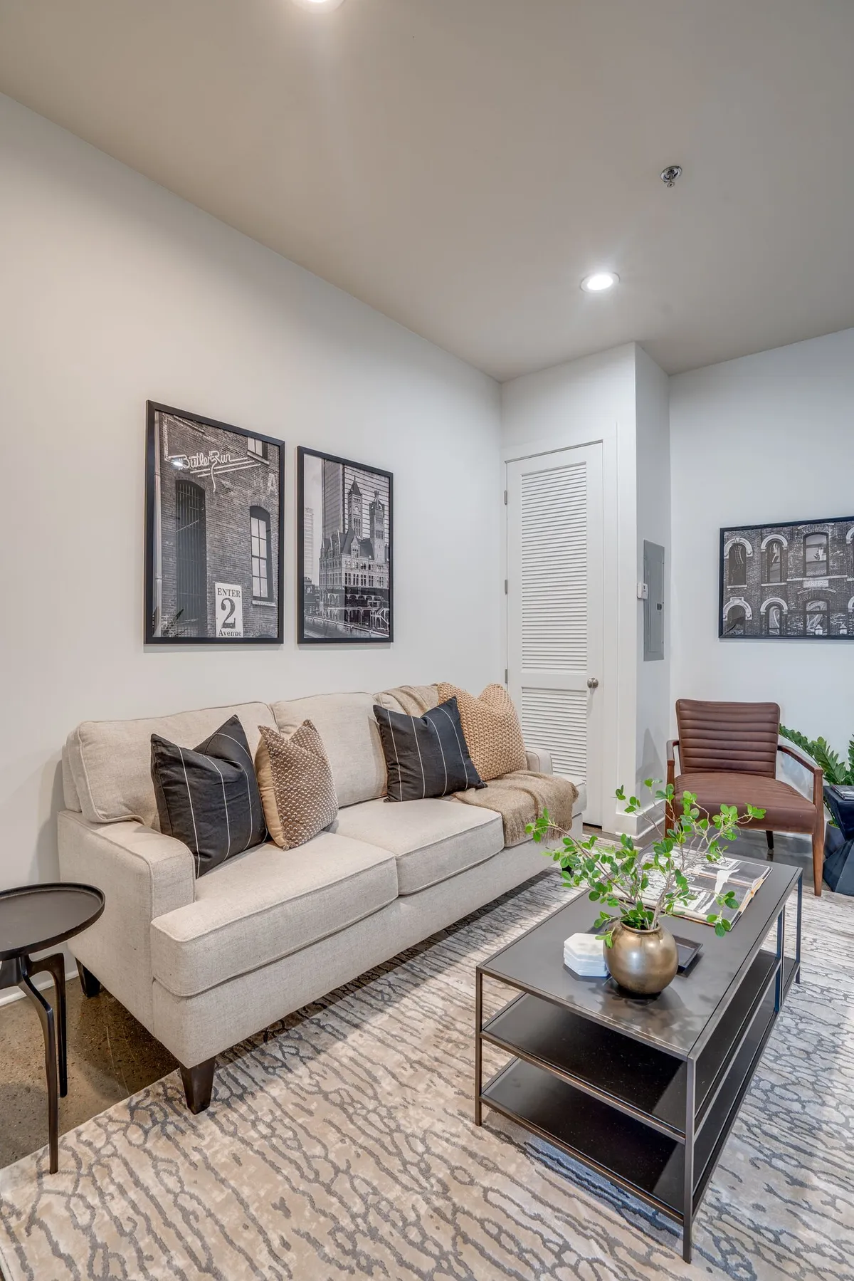 A cozy living room scene with a soft sofa, a central coffee table, leafy plant, and modern wall art. The arrangement naturally draws people together for both relaxation and group chats, with a comfortable and homey atmosphere.