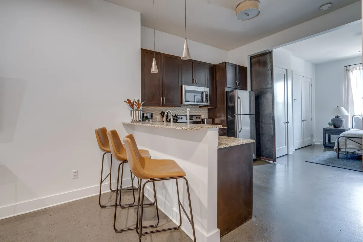 A contemporary kitchen with bar stools lined up along a spacious island. Stainless steel appliances are visible, and the space is well-lit, providing a welcoming atmosphere for casual dining and group entertaining.